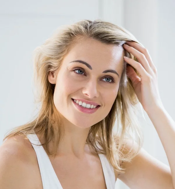 Blonde woman examining her hair looking in a mirror