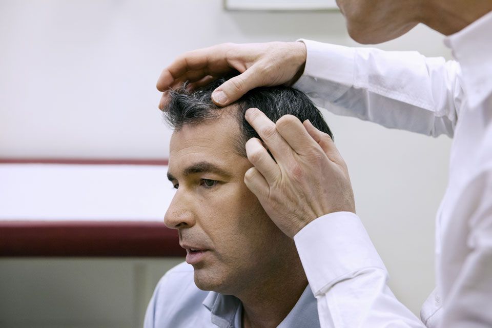 A doctor examining a patient's hairline